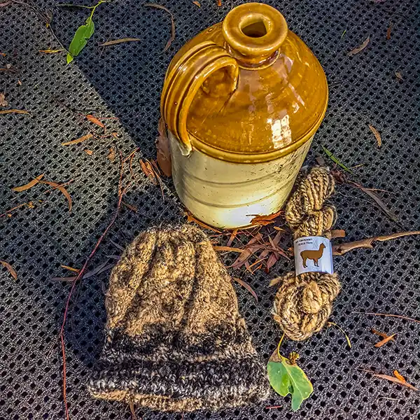 Brown alpaca beanie with a large brown jug and a skein of brown alpaca yarn