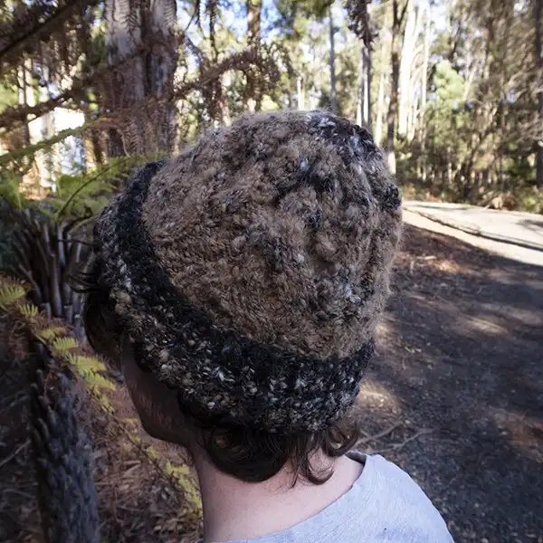 A young man is wearing a brown alpaca beanie