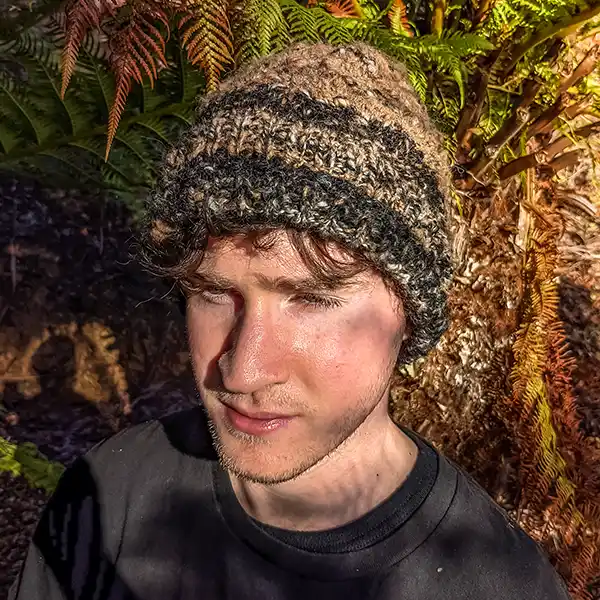 A young man is wearing a brown alpaca beanie