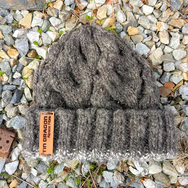 Charcoal beanie displayed on a background of coloured stones