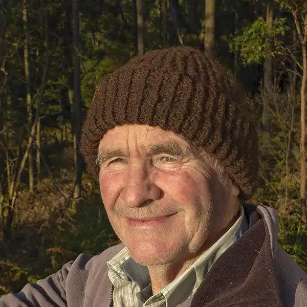 An older man wearing a brown rib-knit beanie i facing the camera