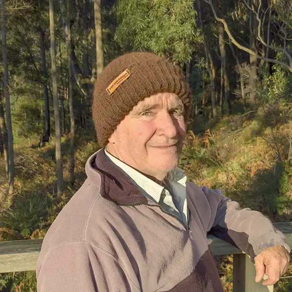 An older man wearing a brown rib-knit beanie is facing the camera side on.