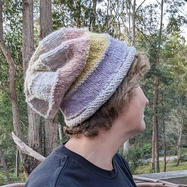 An older woman is wearing a pastel-coloured alpaca slouchy beanie.